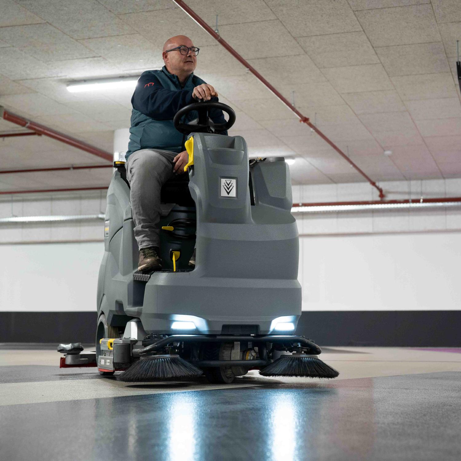 Reino medewerker rijdt op een professionele veegmachine in een parkeergarage