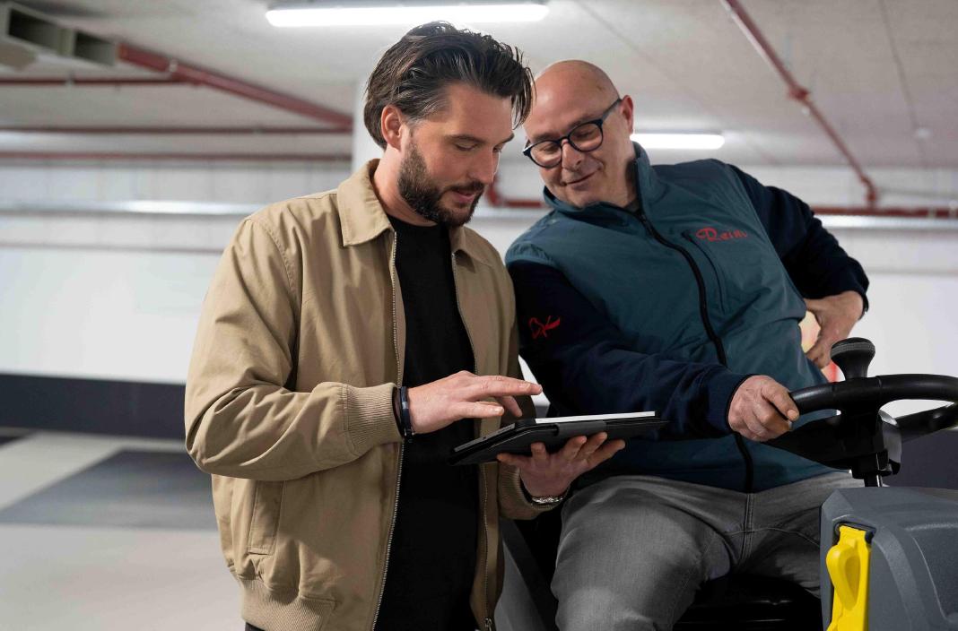 Yannick Nieuwenhoven en een Reino medewerker bekijken een tablet bij een veegmachine