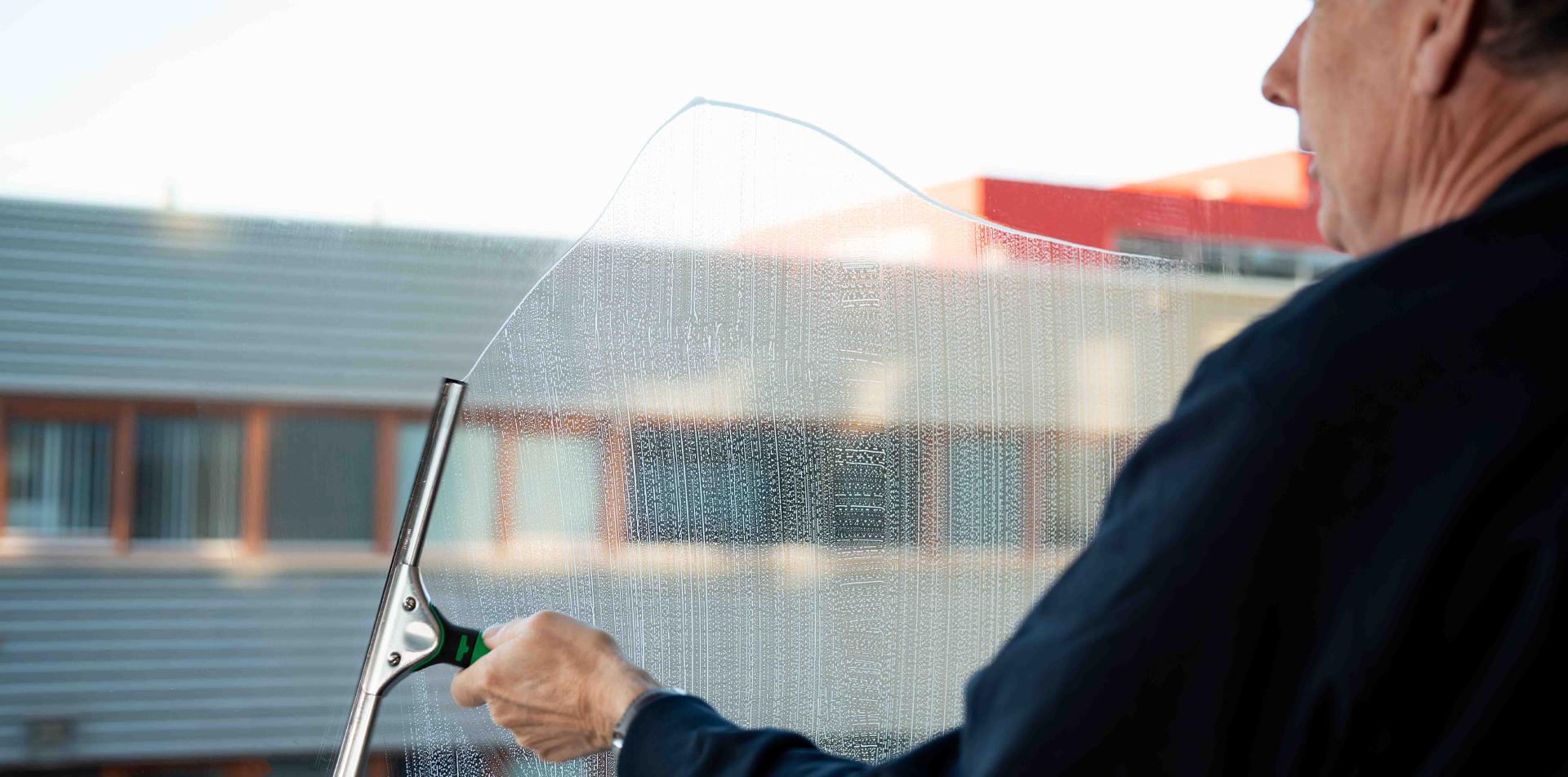 Reino medewerker wast ramen met een trekker op hoogte