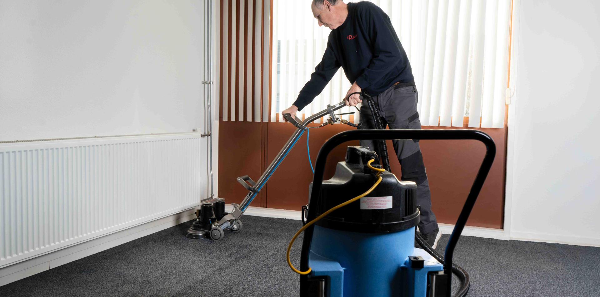 Reino medewerker reinigt tapijt met een professionele tapijtmachine