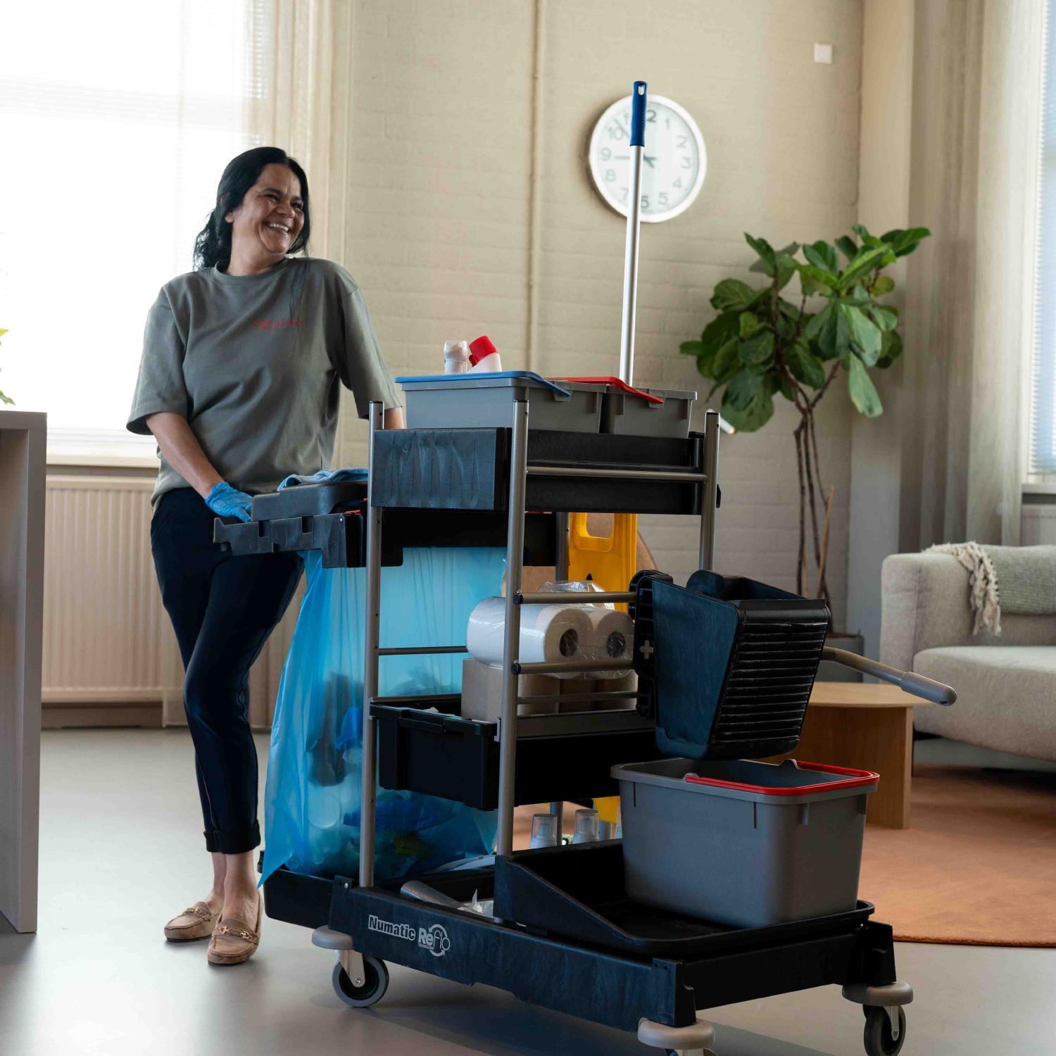 Reino schoonmaakmedewerkster met schoonmaakwagen in kantoorruimte