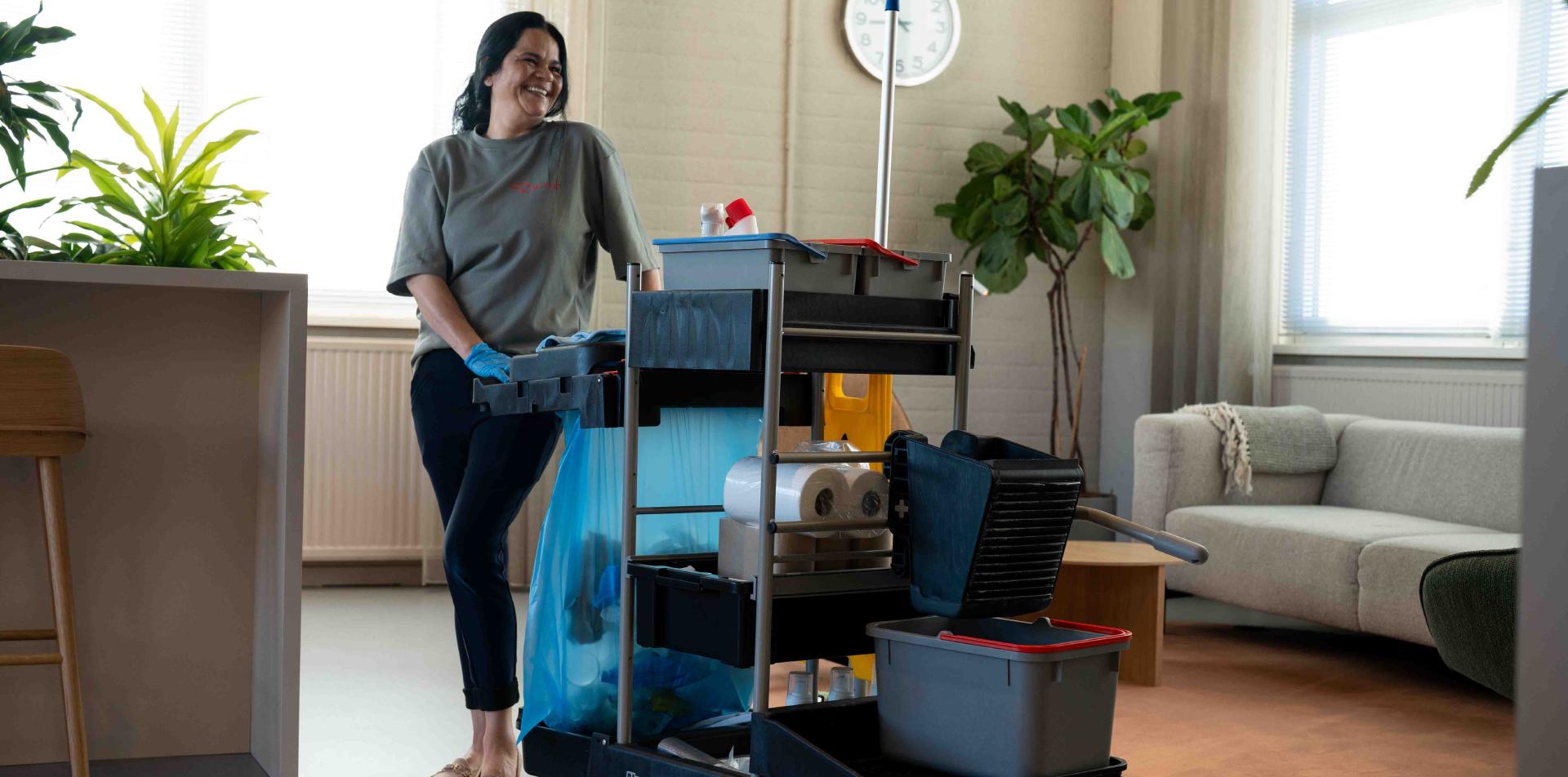 Reino schoonmaakmedewerkster met schoonmaakwagen in kantoorruimte