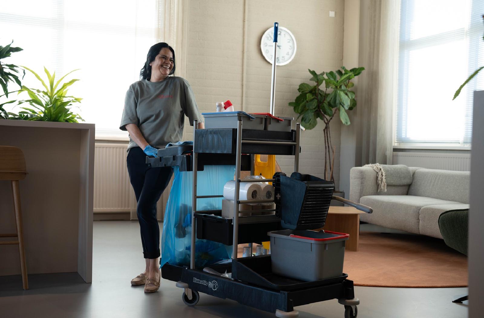 Reino schoonmaakmedewerkster met schoonmaakwagen in kantoorruimte