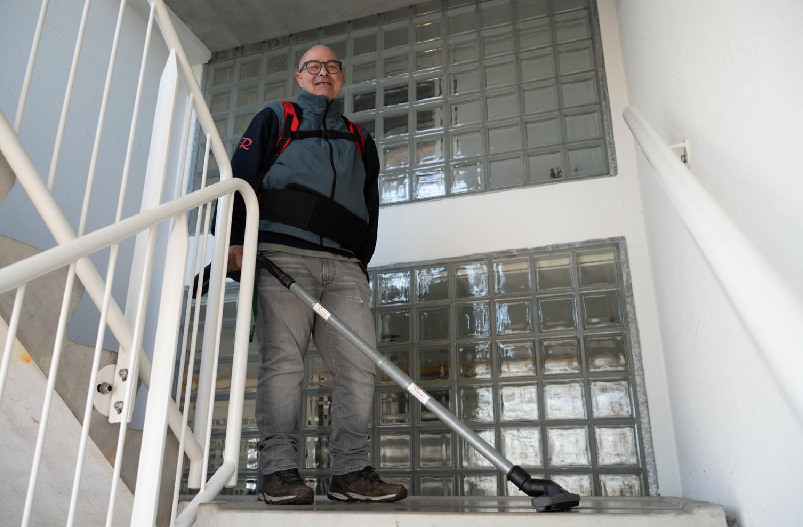 Reino medewerker met rugzak stofzuiger op een trap