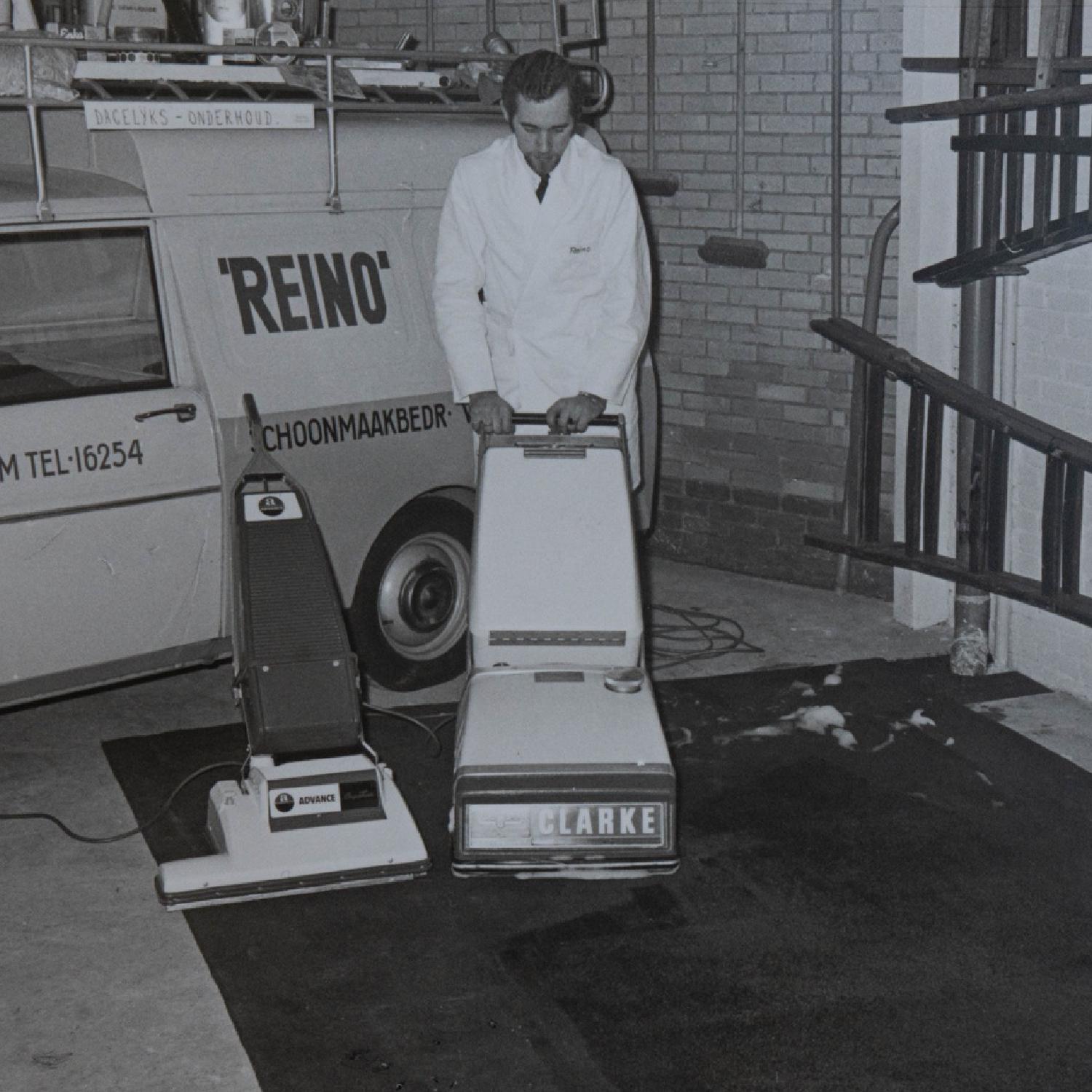 Historische zwart-witfoto van een Reino medewerker bij de bedrijfsbus en vloermachines
