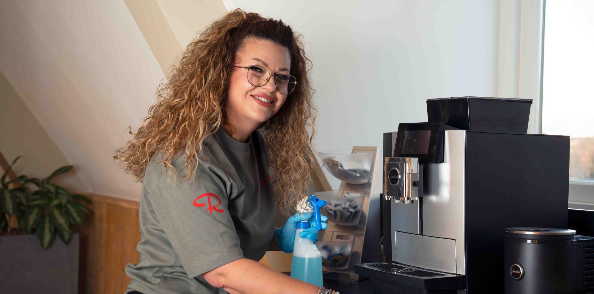 Reino schoonmaakmedewerkster maakt een koffiezetapparaat schoon op kantoor