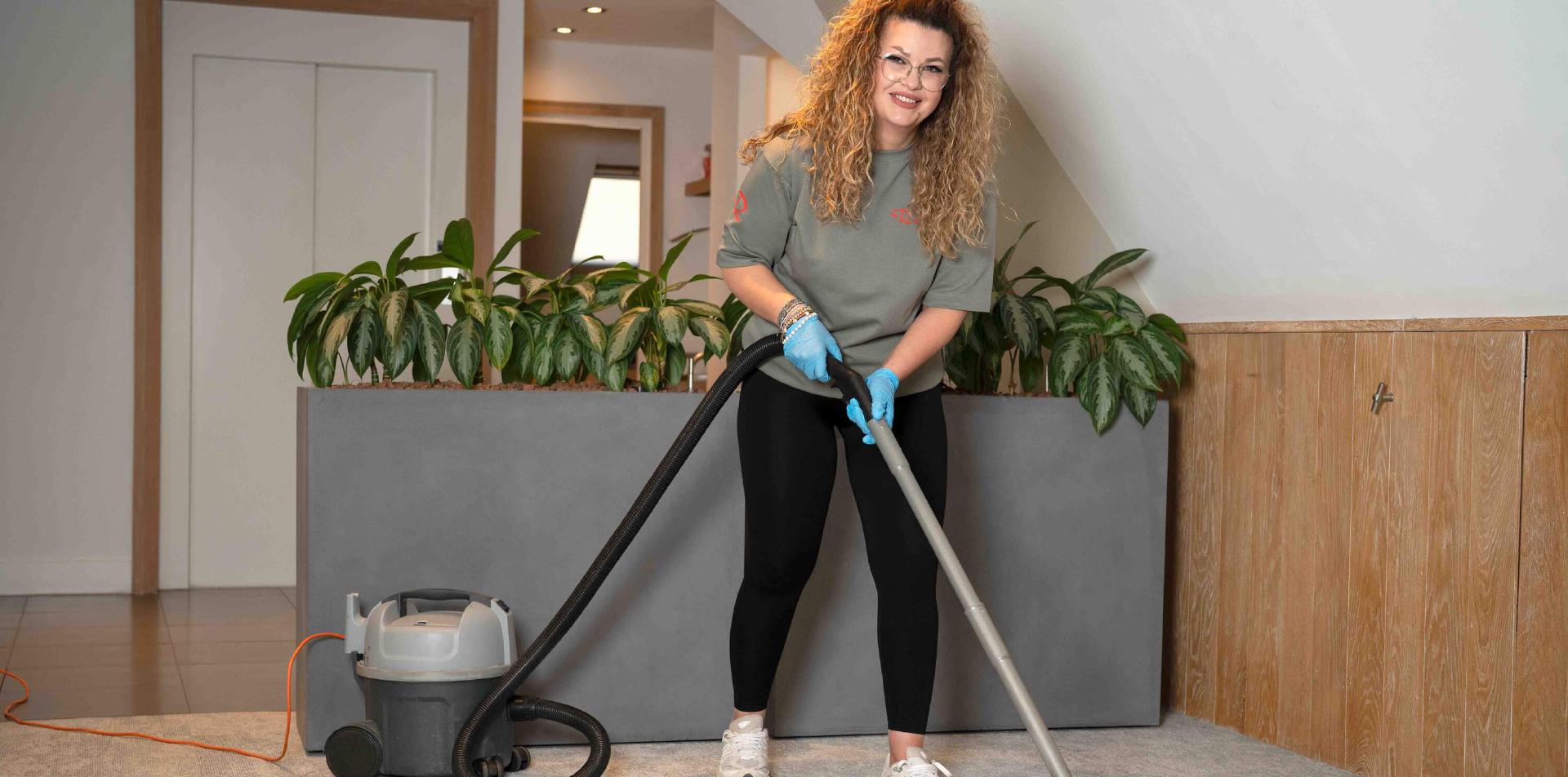 Reino schoonmaakmedewerkster zuigt tapijt met een stofzuiger in een winkel of showroom