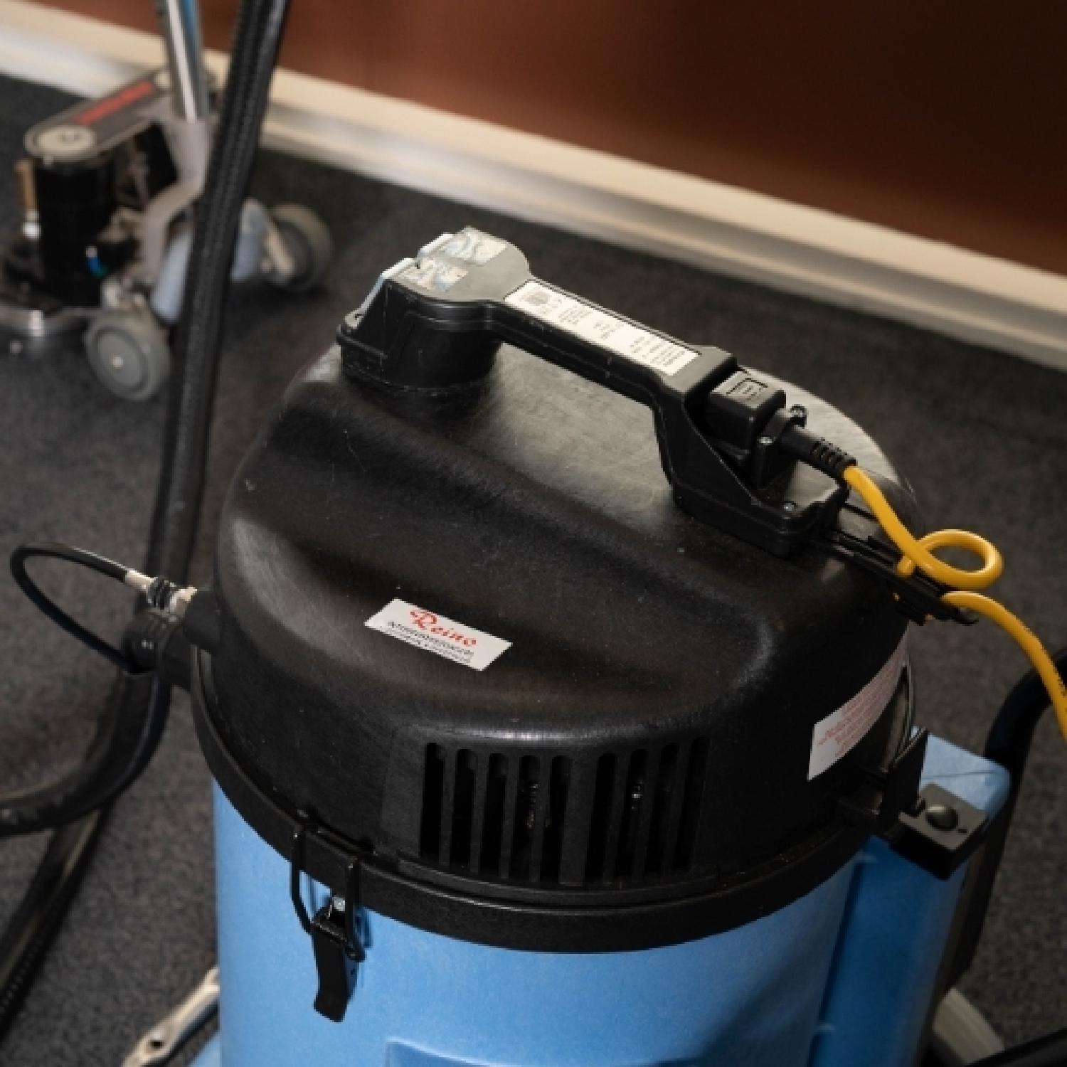 Reino medewerker reinigt een tapijt met een professionele reinigingsmachine
